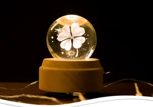 Macro shot of luminous clover crystal ball music box with warm LED wooden base