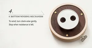 Close-up of the wooden music box base with a mechanical metal clockwork winding mechanism