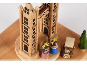 Detalle de caja de música de madera con castillo en miniatura, coche y figuritas