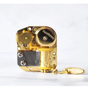 Macro shot of a golden 18-note wind-up music box movement with gear details
