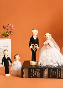 Detailed view of four miniature wooden wedding dolls with lace veils and suits on books
