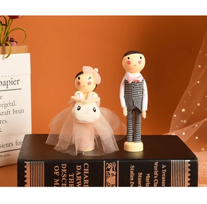 Detail of wooden bride and groom dolls in wedding attire on a black book with warm lighting