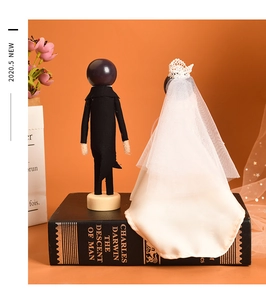 Detail of wooden wedding doll set featuring a groom in tuxedo and bride with lace veil