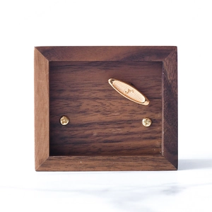 Bottom view of walnut wood music box showing the golden wind-up key and metal mechanism