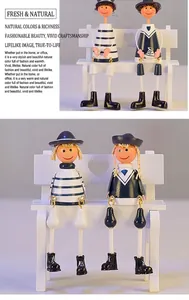 Detail of wooden navy hanging leg dolls sitting on a white bench with heart cutouts