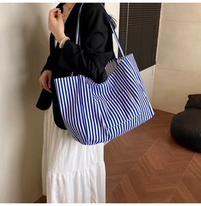 Detail of blue and white striped canvas tote bag with functional front pocket