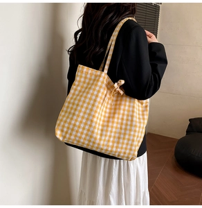 Detail view of yellow checkered canvas tote bag with side bow tie and spacious interior