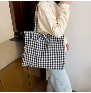 Detail of gingham tote bag featuring a decorative bow tie and spacious interior design