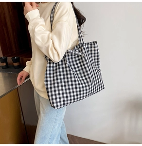 Close-up of black and white checkered canvas tote bag with decorative side bow knot