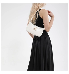 Minimalist white leather underarm bag with gold buckle shown on a black dress model
