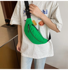 Detail of green nylon waist bag featuring black adjustable strap and multi-pocket design