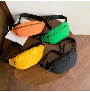 Flat lay of four colorful nylon crossbody bags in orange, green, yellow and black on a table