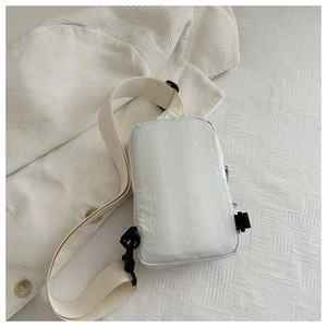 Close-up of white nylon crossbody bag with adjustable wide strap and plastic buckle