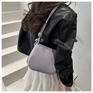 Detail view of purple faux leather crossbody bag featuring knot strap and fashion lettering