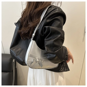 Silver metallic tote bag with bow detail shown on a shoulder in a lifestyle street style