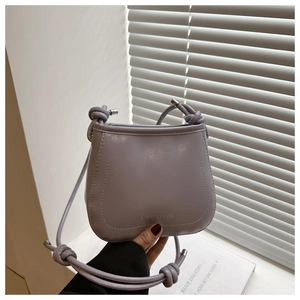 Close-up of lilac leather bucket bag with knotted handle and fashion text detail