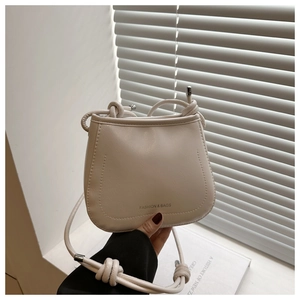 Detail of cream-colored bucket bag with thick rope strap and fashion text logo