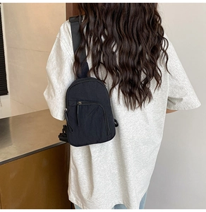 Rear view of a black nylon mini crossbody chest bag with adjustable strap on a white T-shirt