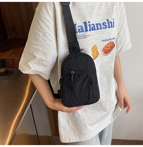 Close-up of lightweight black mini chest bag featuring an adjustable strap and front zipper pocket