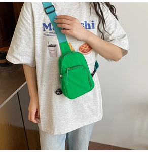 Detail of green nylon crossbody bag with teal strap worn by a model in casual setting