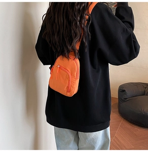 Close-up of lightweight mini orange nylon chest bag with adjustable strap and zipper