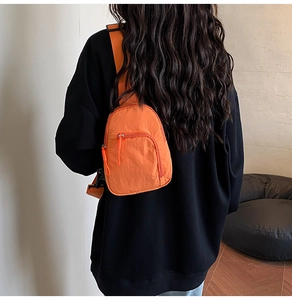 Detail of an orange lightweight nylon chest bag with zipper pocket and adjustable strap