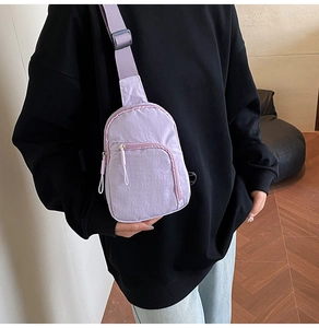 Close-up of a purple nylon mini chest bag with adjustable strap and dual zipper pockets