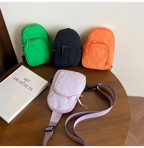 Nylon crossbody bags in green, black, orange, and purple on a wooden table