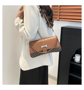 Detail of the H-shaped metal buckle and brown leather pattern on the shoulder bag