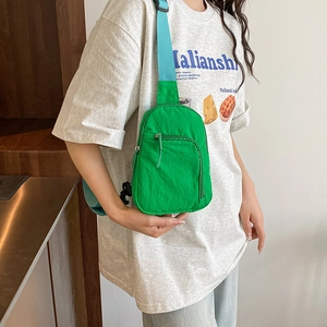 Green lightweight sporty chest bag with light blue strap shown on a casual model
