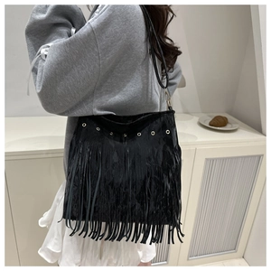 Détail du sac à bandoulière en daim noir avec œillets métalliques et longues franges