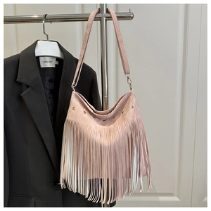 Detail of light pink crescent bag featuring long tassels and metallic eyelet trim