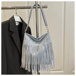 Detail view of light blue bohemian tassel bag with metal eyelets and long suede fringe