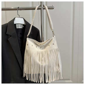 Detailed close-up of a white fringe hobo bag with long tassels and metallic eyelets