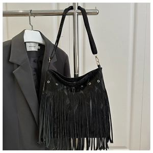Detail of black fringe tote bag with velvet texture and metallic eyelets on suit background