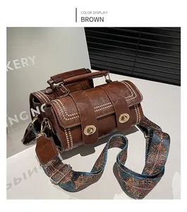 Detail view of brown leather crossbody bag with rivet trim and ethnic patterned wide strap