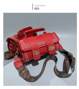Top view of red leather cylindrical handbag with golden rivets and ethnic strap detail