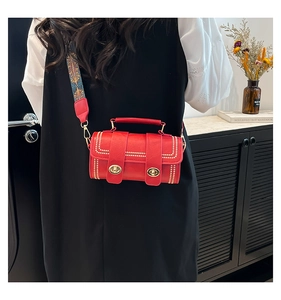 Detail of red cylinder bag with ethnic embroidered strap and golden twist locks