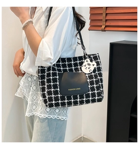 Dettaglio della borsa tote in lana pied de poule con tasca in pelle nera e ciondolo tigre