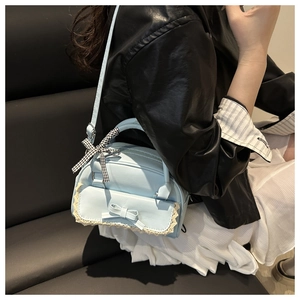 Nahaufnahme hellblaue Handtasche mit Schleife, Spitze und Band am Model getragen