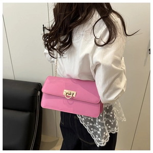 Close-up of pink glossy patent leather bag with gold ring buckle and chain strap