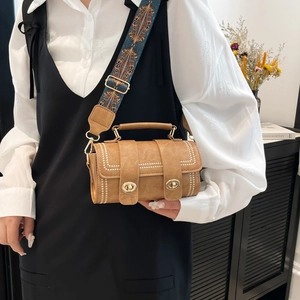 Brown vintage cylinder crossbody bag with studded pattern and ethnic style wide strap