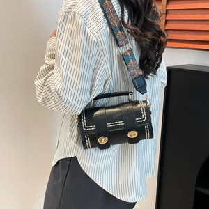 Black cylinder crossbody bag with ethnic woven strap and white dotted geometric patterns