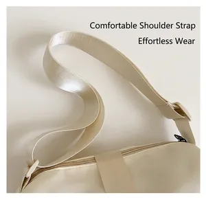 Detail of adjustable wide fabric shoulder strap on a beige nylon pillow crossbody bag