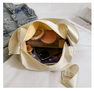 Interior capacity of the beige nylon crossbody bag showing storage for phone and cosmetics