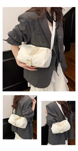 Three-way view of a cream oxford crossbody bag worn by a model in a grey blazer suit