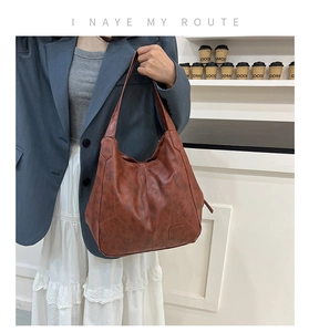 Detailed macro view of the brown leather shoulder bag with embossed logo on the bottom