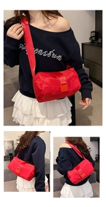 Close-up of vibrant red nylon cylinder bag with wide strap and buckle details