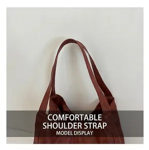 Close-up of wide leather shoulder strap with durable reinforced stitching on brown tote bag