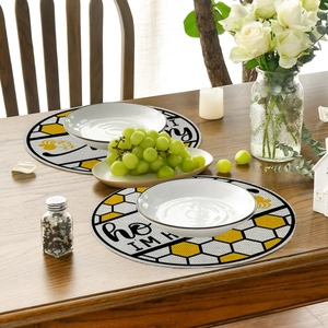 Detailed view of round bee-themed linen placemat with Honey I'm Home text on wooden table